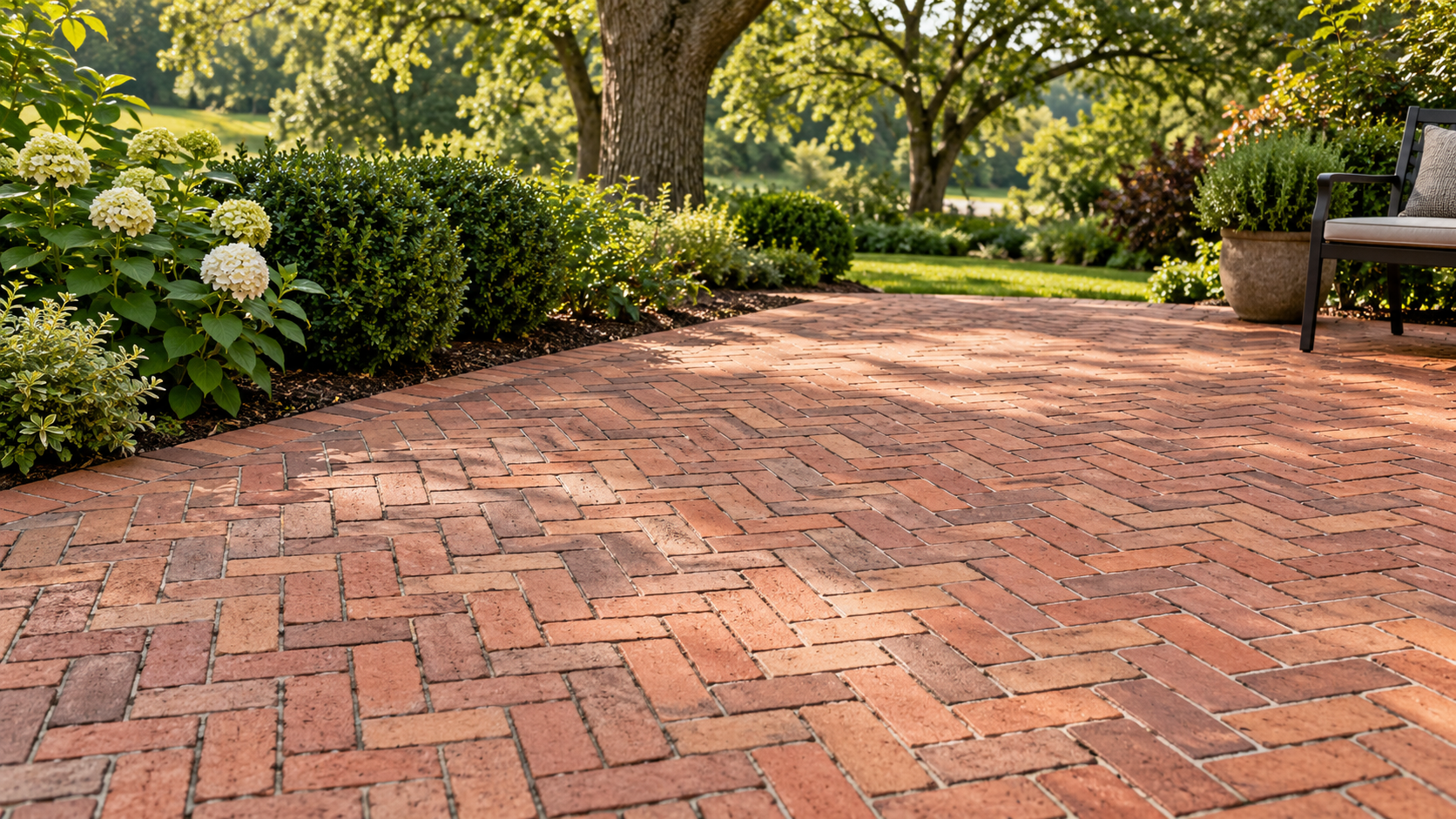 Illustrative red brick patio in a herringbone pattern with a garden border
